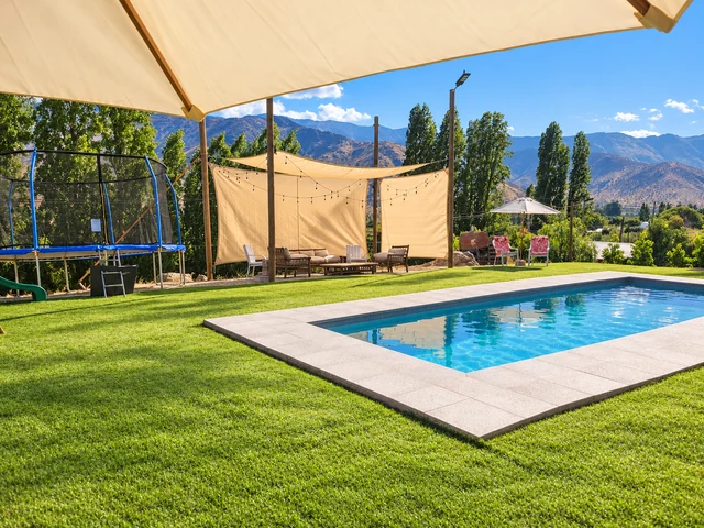 Otra vista del recinto: piscina, terraza con sombra y montañas al fondo